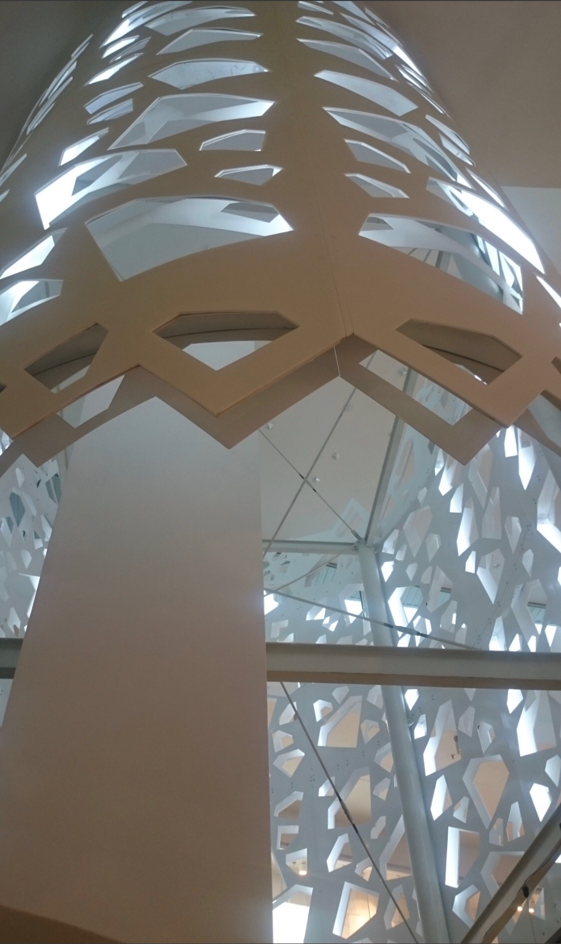 Ażurowa konstrukcja stalowa w budynku w Warszawie, widok z dołu ukazuje geometryczny wzór wycięty w metalu i jasne wnętrze hali.