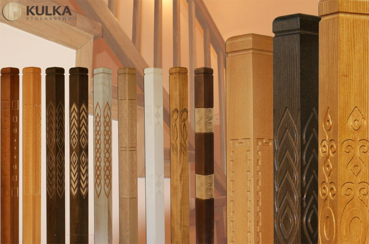 Różnorodne, zdobione drewniane słupki balustrady schodowej w ciepłych odcieniach, prezentujące unikalne wzory i wykończenia, ustawione w rzędzie na tle schodów.