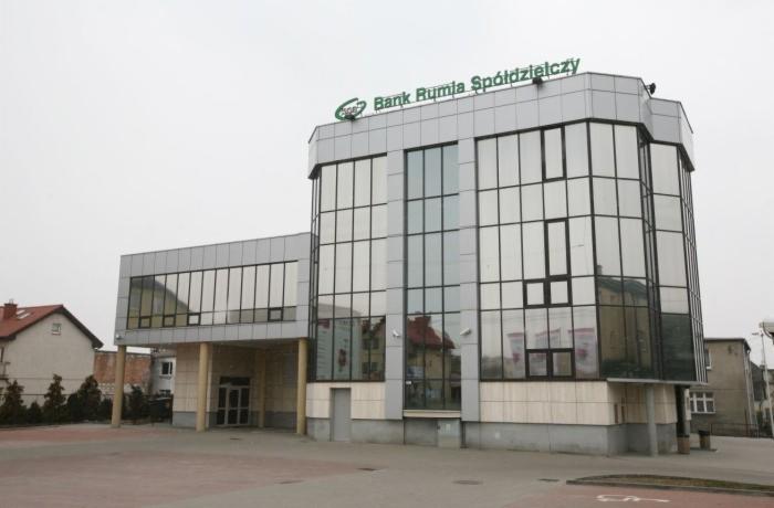 Bank Rumia Spółdzielczy: nowoczesny budynek z aluminiową fasadą i dużymi oknami, widok z zewnątrz w pochmurny dzień. Architektura komercyjna z elementami szkła.