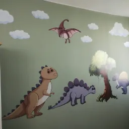 Malowidło ścienne w pokoju dziecięcym przedstawiające dinozaury i chmury na oliwkowozielonym tle, wykonane farbami w odcieniach brązu, szarości i bieli.
