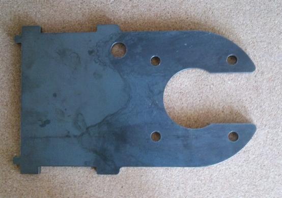 Precyzyjnie wycięty, surowy element metalowy z otworami i wycięciem w kształcie litery C, leżący na neutralnym tle. Widoczne ślady obróbki.