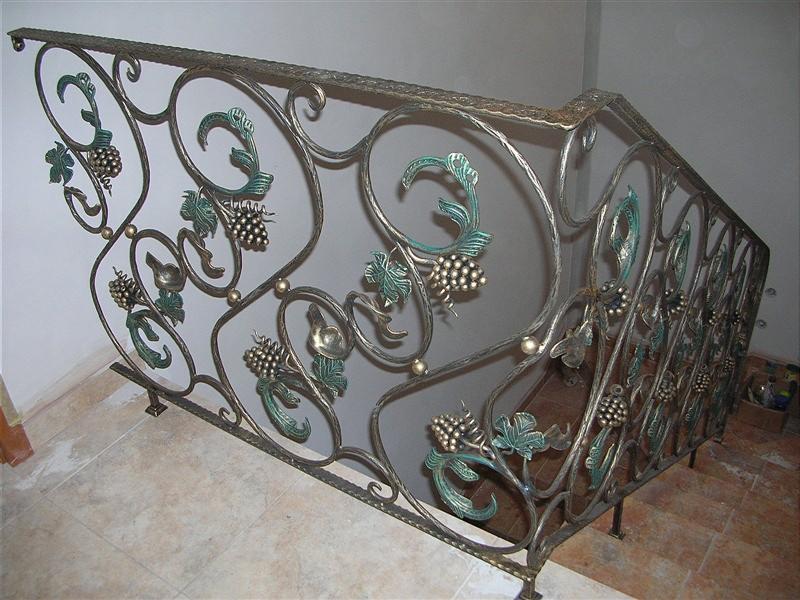 Kute, metalowe balustrady schodowe z motywem winogron, malowane na złoto i zielono. Dekoracyjne, ręcznie robione zdobienia.