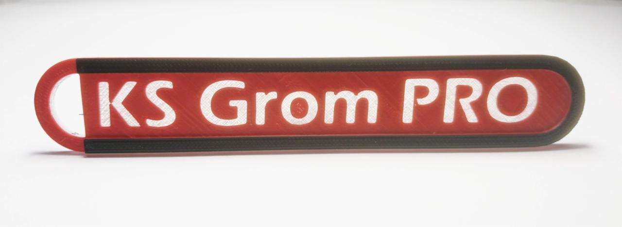 Czerwono-czarny szyld z napisem 'KS Grom PRO' na białym tle.