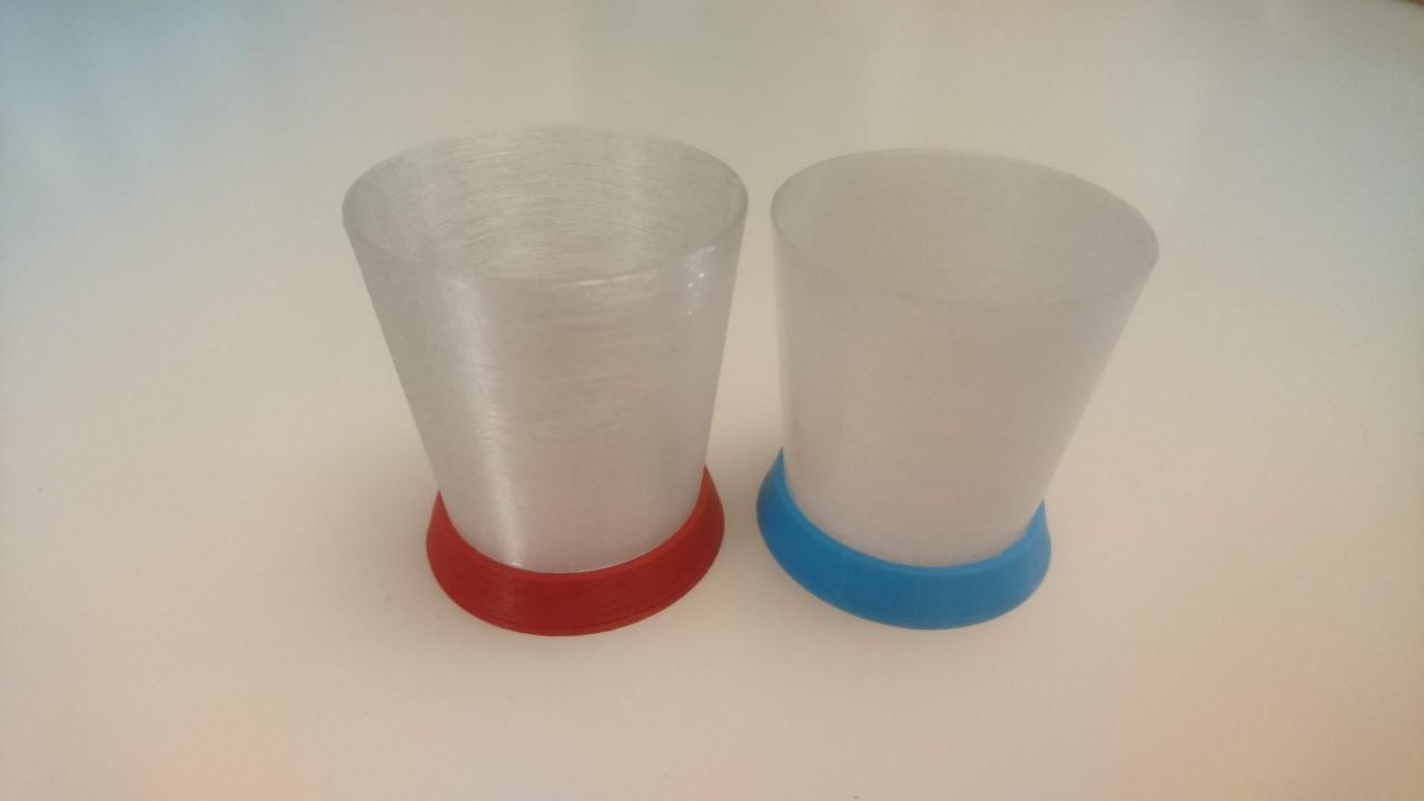 Dwa stożkowe elementy izolacyjne z tworzywa sztucznego, jeden z czerwoną, a drugi z niebieską podstawą, wydrukowane w technologii 3D.