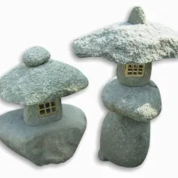 Dwa kamienne lampiony ogrodowe w stylu japońskim, o różnej wysokości i kształcie daszków, oświetlone z góry, na białym tle. Dekoracyjny element architektury krajobrazu.