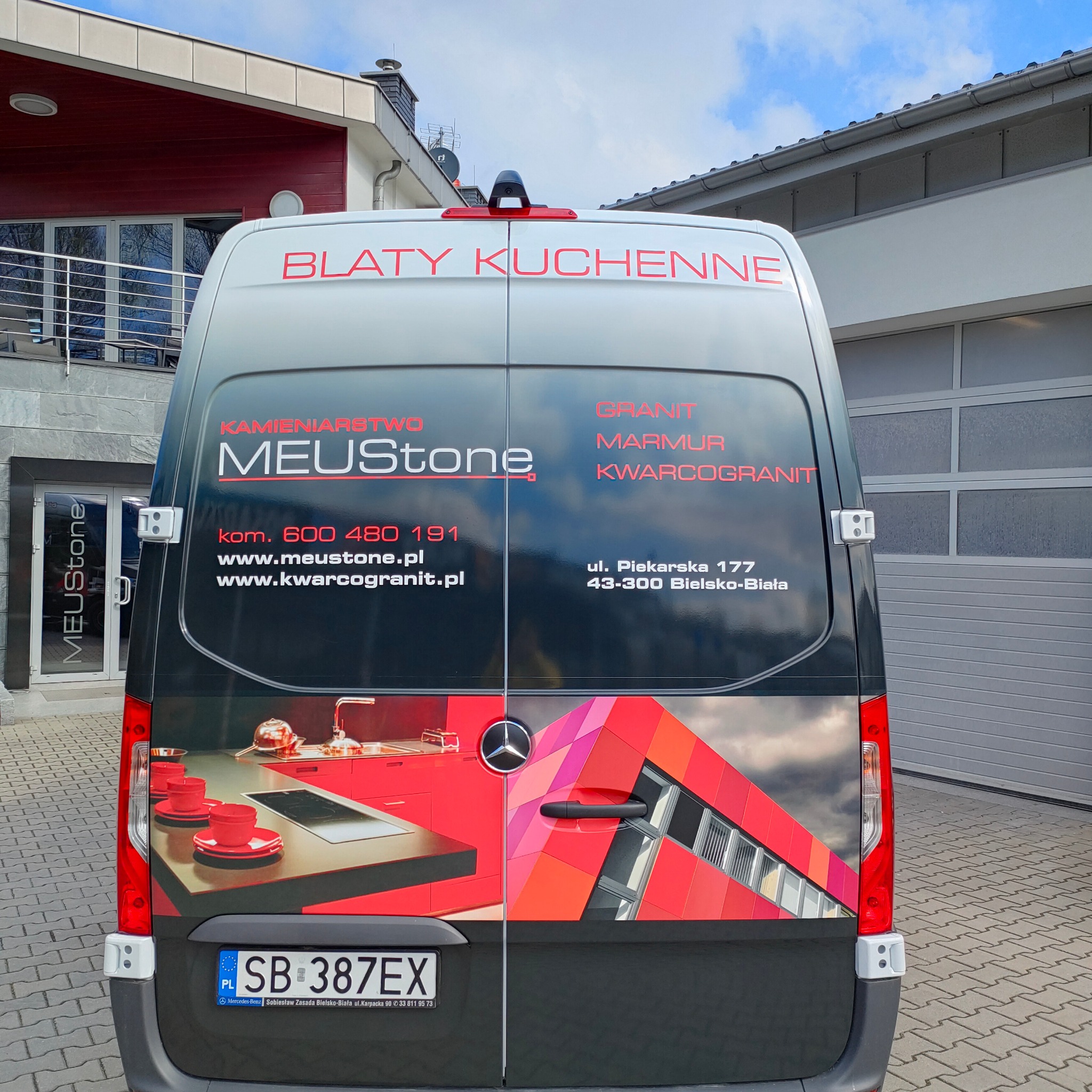 Oklejony samochód firmy kamieniarskiej MeUStone z reklamą blatów kuchennych, granitu, marmuru i kwarcogranitu. Czerwono-czarna grafika na tylnych drzwiach.