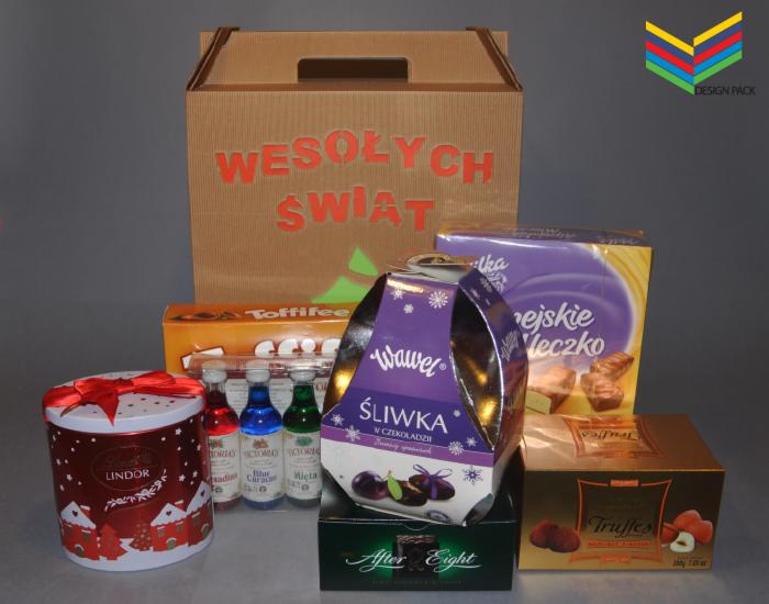 Zestaw słodyczy różnych marek, w tym Lindor, Wawel Śliwka w czekoladzie, Toffifee, Mleczna czekolada, Truffes, After Eight, oraz trzy małe buteleczki z barwnikami spożywczymi, umieszczone na szarym...