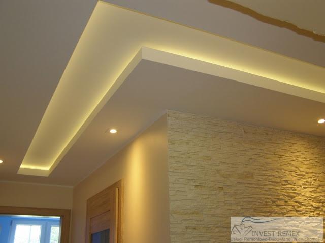 Nowoczesny sufit podwieszany z oświetleniem LED w kształcie litery L, dekoracyjna ściana z kamienia, widok z dołu.