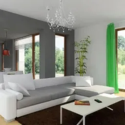 Jasne, przestronne wnętrze domu z otwartą kuchnią i salonem. Nowoczesny design z dużymi oknami i widokiem na zieleń. Minimalistyczny wystrój z akcentami kolorystycznymi.