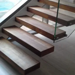 Nowoczesne schody z drewnianymi stopniami i szklanymi balustradami, widok z dołu, obok jacuzzi.