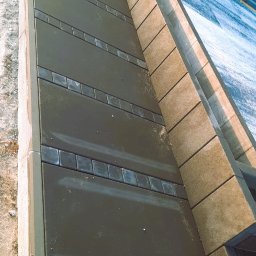 MOFFIJ Bruk - Ukończona nawierzchnia z ciemnej kostki z dekoracyjnymi wstawkami, obrzeża z jasnej kostki. Widok z góry, ukośne ujęcie.