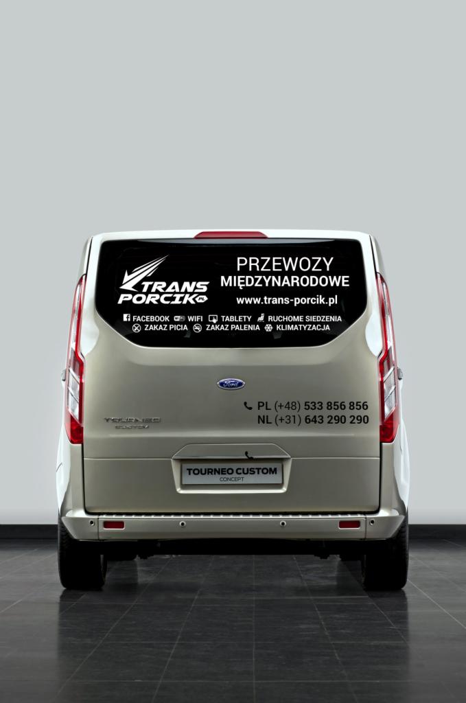 Tył złotego busa Tourneo Custom z naklejką firmy Trans Porcik oferującej przewozy międzynarodowe, z informacją o WiFi, tabletach i klimatyzacji.