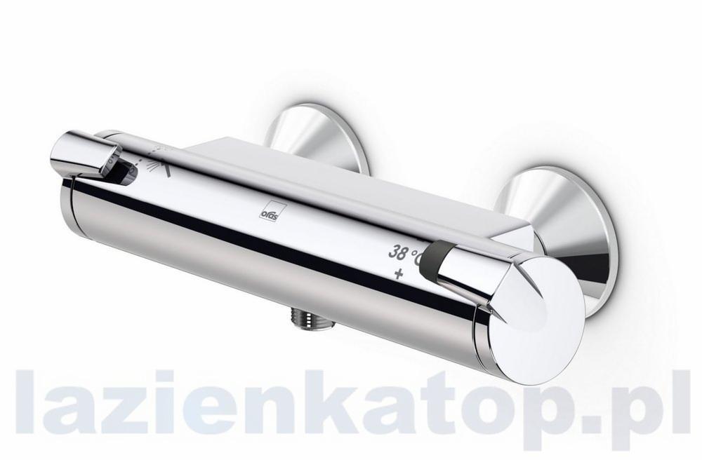 Bateria prysznicowa Oras Optima z termostatem, chromowana, widok z boku, zamontowana na białej ścianie, z widocznym oznaczeniem temperatury 38 stopni Celsjusza.