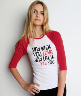 Kobieta w białej koszulce z czerwonymi rękawami 3/4, z czarno-czerwonym napisem 'Find What You LOVE and Let It KILL YOU', pozuje z ręką na biodrze.