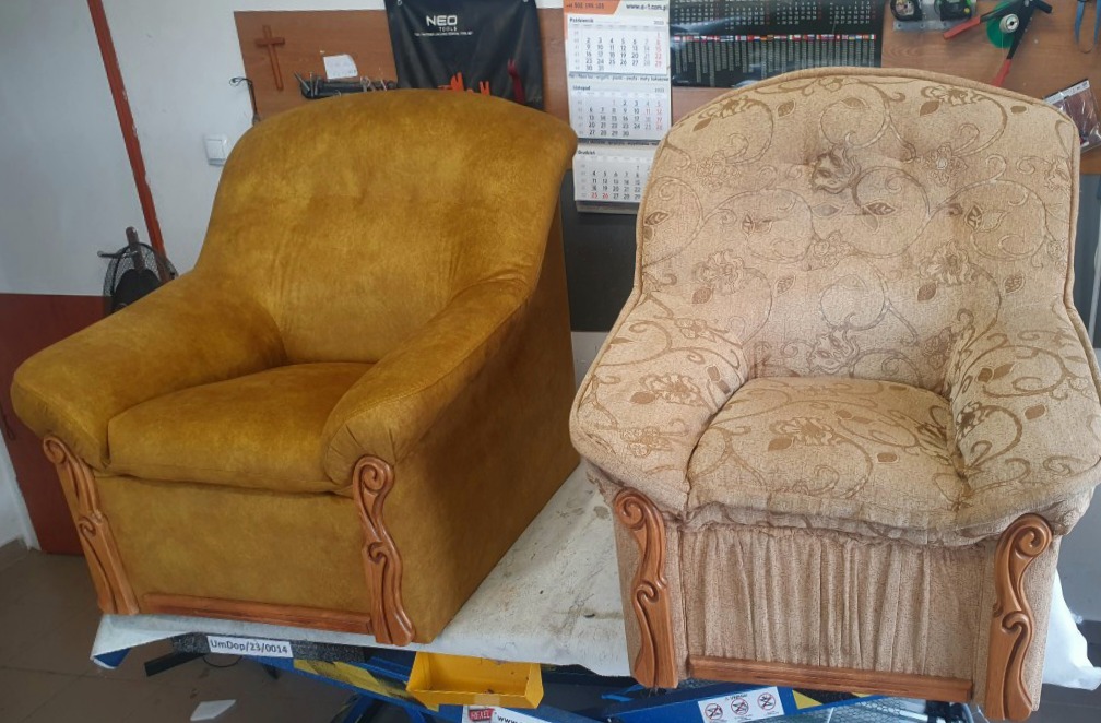 Dwa fotele: jeden w odcieniach złota z gładką tkaniną, drugi w beżowe kwiaty, oba z drewnianymi, zdobionymi podłokietnikami, stojące na podnośniku warsztatowym.