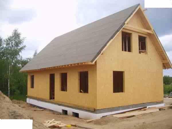 Surowy stan domu szkieletowego z widocznymi otworami okiennymi i drzwiami w Zielonej Górze, przed pracami wykończeniowymi.