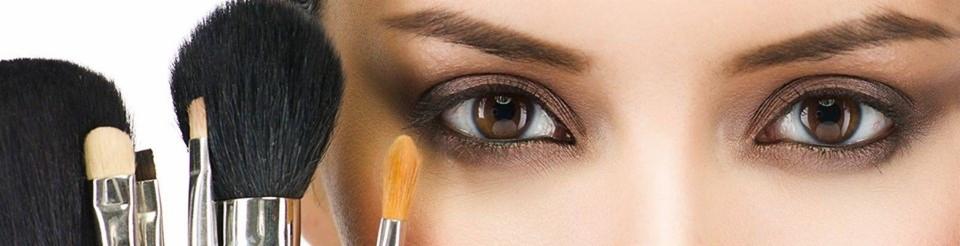 Zbliżenie na kobiece oko z brązowym makijażem i zestaw pędzli do aplikacji kosmetyków w srebrnych oprawkach.