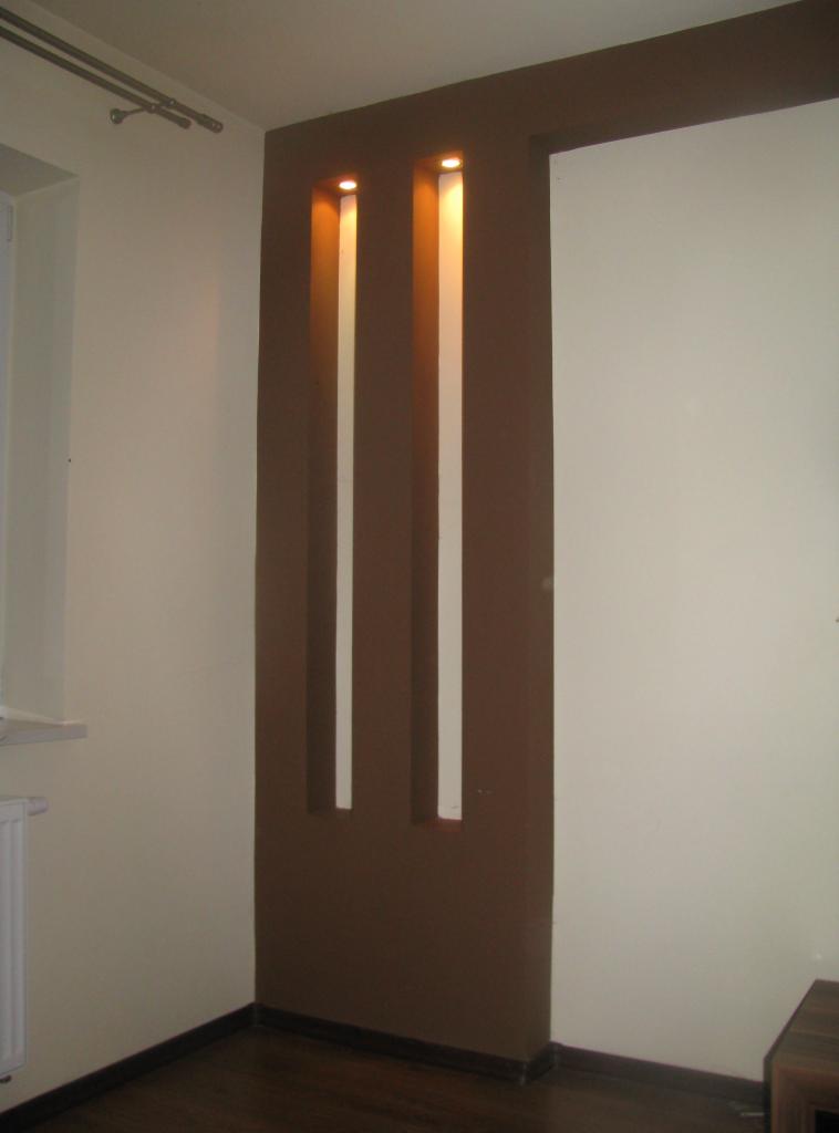 Brązowa ściana z podświetlanymi wnękami w Niepołomicach. Nowoczesny design wnętrza, kremowe ściany, ciemna podłoga. Dekoracyjne oświetlenie.