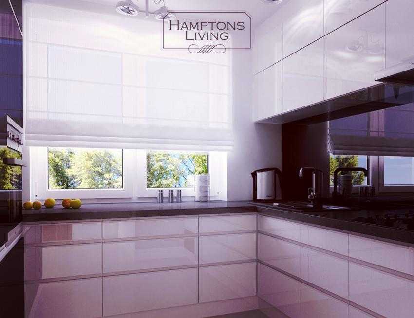 Nowoczesna kuchnia w bieli i czerni z połyskującymi frontami szafek, dużym oknem z roletą rzymską i widokiem na zieleń. Na blacie owoce i czajnik.