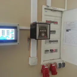 Rozdzielnia elektryczna z otwartymi drzwiami, kontroler Afrisko, panel Weintek z danymi, czerwone wtyczki. Widoczne bezpieczniki i listwa zaciskowa.