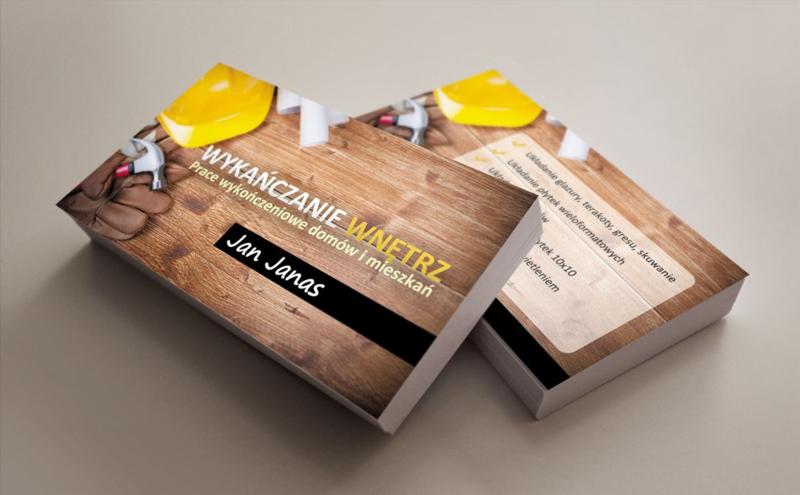 Dwie wizytówki z drewnianym tłem, motywem narzędzi i tekstem 'Wykańczanie wnętrz', 'Jan Janas'. Jedna wizytówka leży na drugiej, eksponując detale.