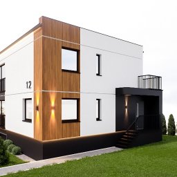 Biuro Projektów i Realizacji Inwestycji GP - Wizualizacja dwukondygnacyjnego domu z numerem 12, z elementami drewnianej elewacji i czarnymi akcentami, otoczonego zielenią. Nowoczesny design z oświetleniem zewnętrznym.
