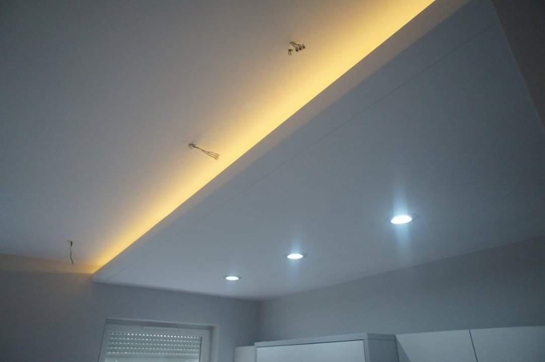 Biały sufit podwieszany z oświetleniem LED: listwa świetlna i punktowe lampy, widoczne wystające przewody elektryczne.