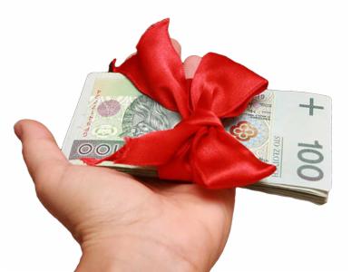 Dłoń trzymająca plik banknotów 100 zł przewiązanych czerwoną kokardą na białym tle. Symbol prezentu finansowego, nagrody lub gotówki.