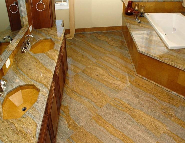 Ekskluzywna łazienka z blatem z kamienia naturalnego i podłogą z płytek imitujących kamień, z umywalkami wpuszczanymi i wanną obudowaną kamieniem.