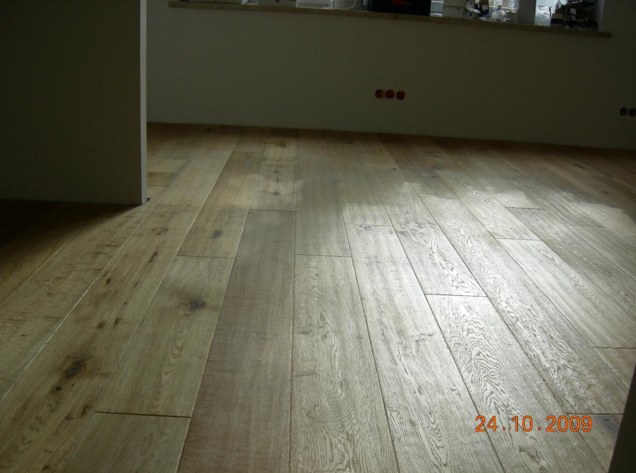 Wycyklinowana, drewniana podłoga w odcieniach beżu i brązu, z widoczną datą 24.10.2009 w prawym dolnym rogu, prezentująca efekt renowacji.
