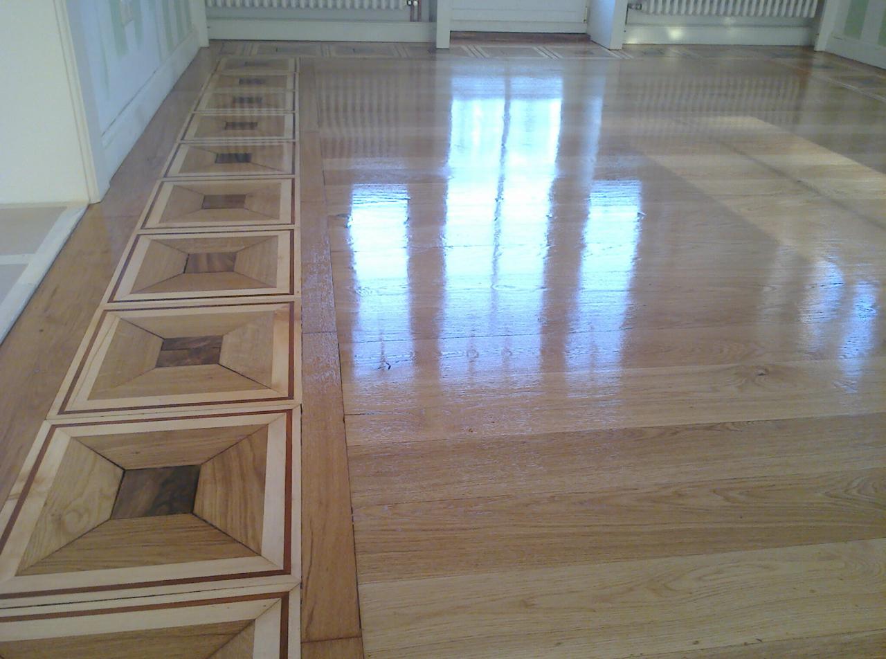 Parkiet z dekoracyjnym wzorem kwadratów, świeżo po cyklinowaniu, z połyskującą powierzchnią odbijającą światło okien.