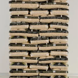 Stos worków z pelletem ułożonych na drewnianej palecie, widoczne napisy 'The Best Quality' i waga 15 kg na czarnych etykietach.