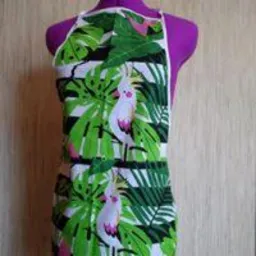 Fartuch kuchenny z motywem tropikalnych liści i papug kakadu, prezentowany na fioletowym manekinie krawieckim.