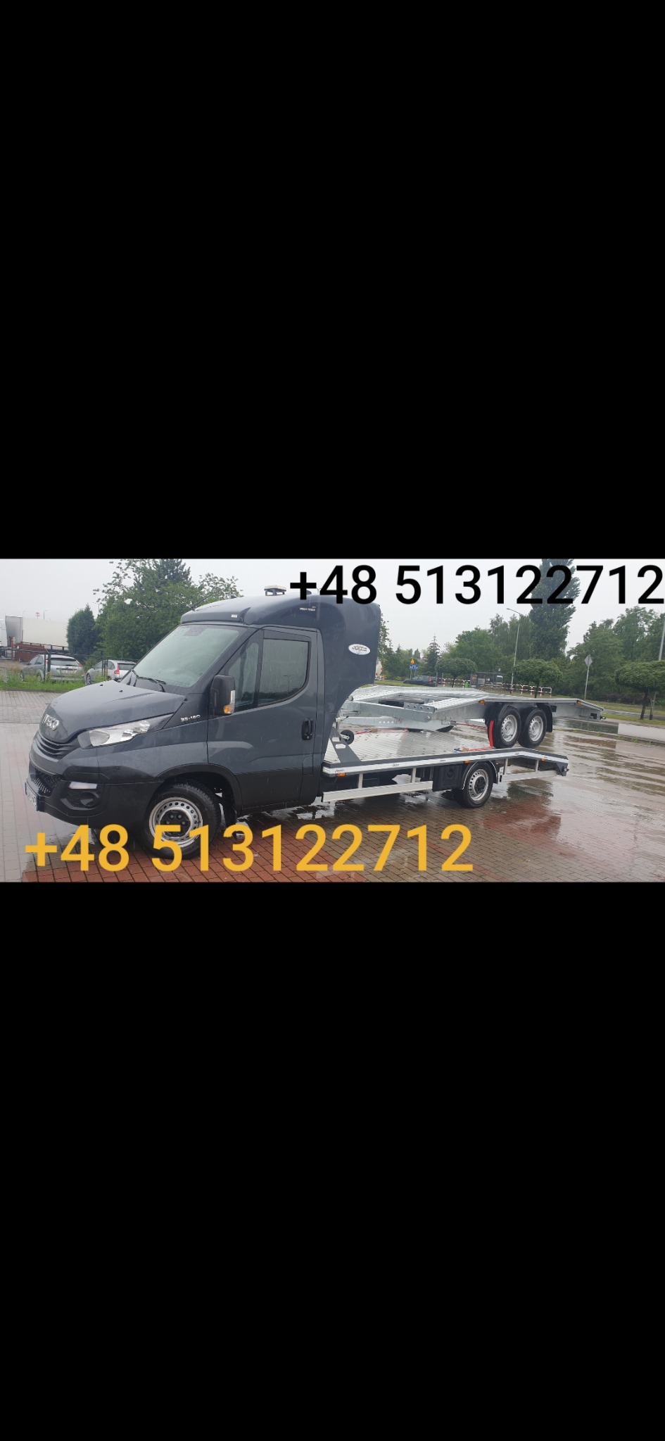 Szara laweta z platformą najazdową na parkingu w pochmurny dzień, widoczny numer telefonu kontaktowego.