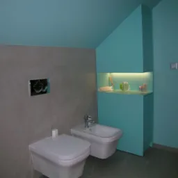 Nowoczesna łazienka w odcieniach szarości i turkusu z podwieszaną toaletą, bidetem i szafką z oświetleniem LED.