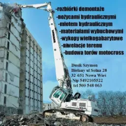 Biała maszyna budowlana Liebherr z długim ramieniem rozbiera wysoki budynek. Gruz leży na ziemi. Widoczny adres firmy i zakres usług.