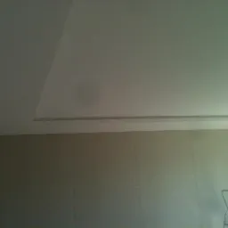 Wykończony sufit podwieszany z listwą dekoracyjną i ściany przygotowane do malowania. Widoczna drabina malarska.