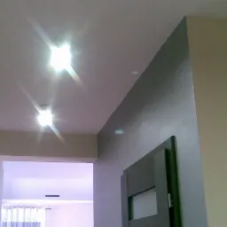 Wnętrze po szpachlowaniu: gładkie, dwukolorowe ściany podświetlone punktowo, widok na sąsiednie pomieszczenie. Nowoczesny design, świeżo wykończone wnętrze.