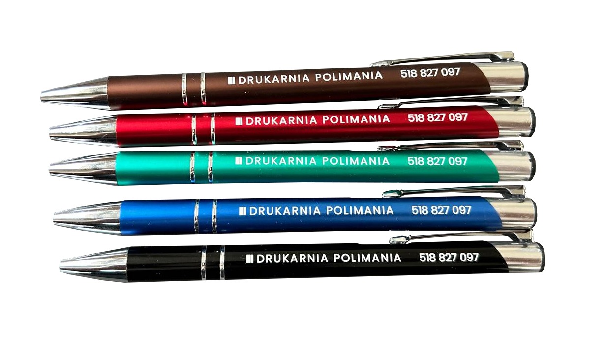 Zestaw pięciu długopisów w kolorach brązowym, czerwonym, zielonym, niebieskim i czarnym z nadrukiem nazwy drukarni 'DRUKARNIA POLIMANIA' i numeru telefonu 518 827 097 na białym tle.