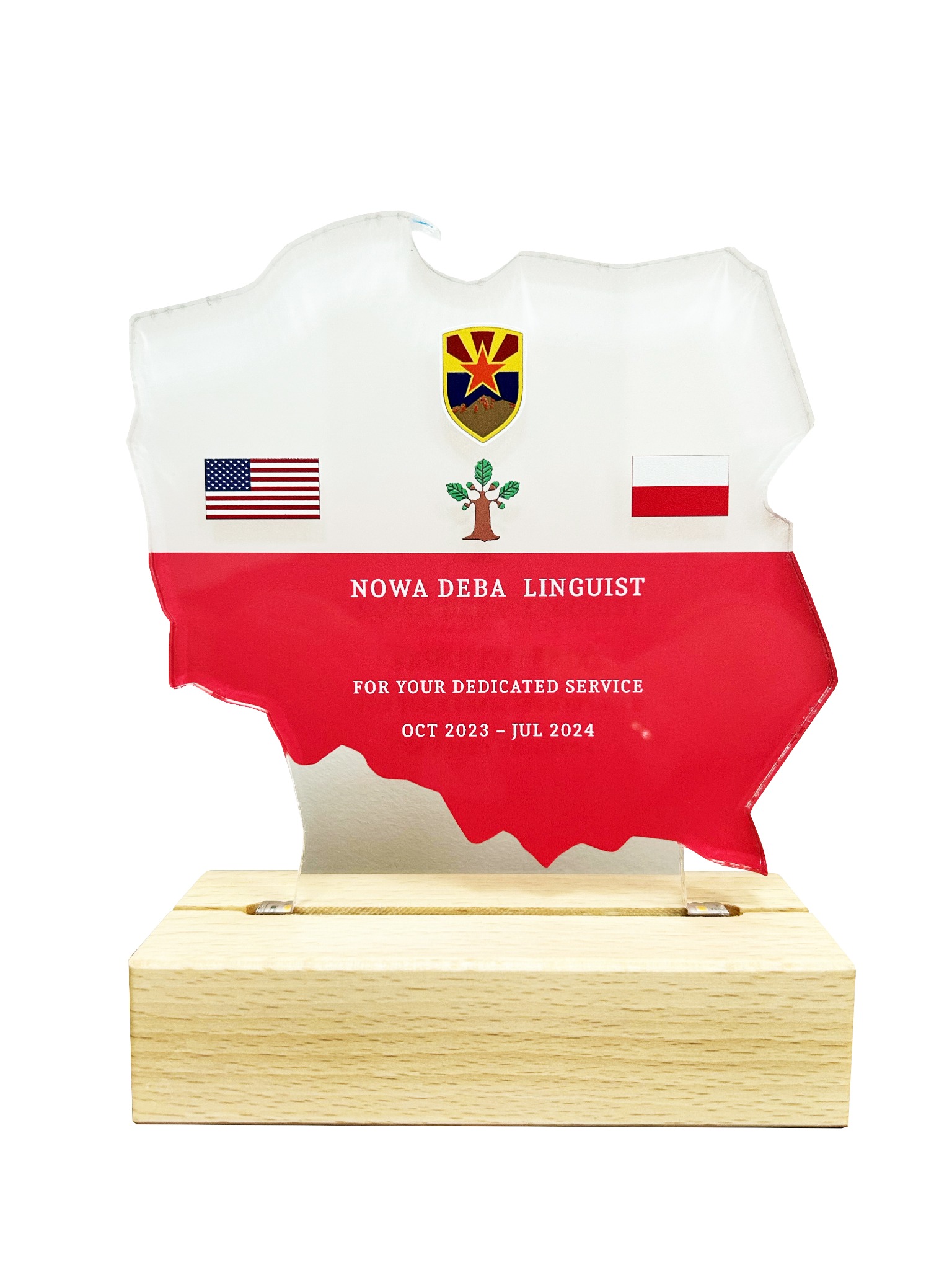 Pamiątkowa statuetka w kształcie mapy Polski, z flagami USA i Polski oraz herbem, umieszczona na drewnianej podstawie. Statuetka upamiętnia służbę dla Nowej Dęby Linguist w latach 2023-2024.