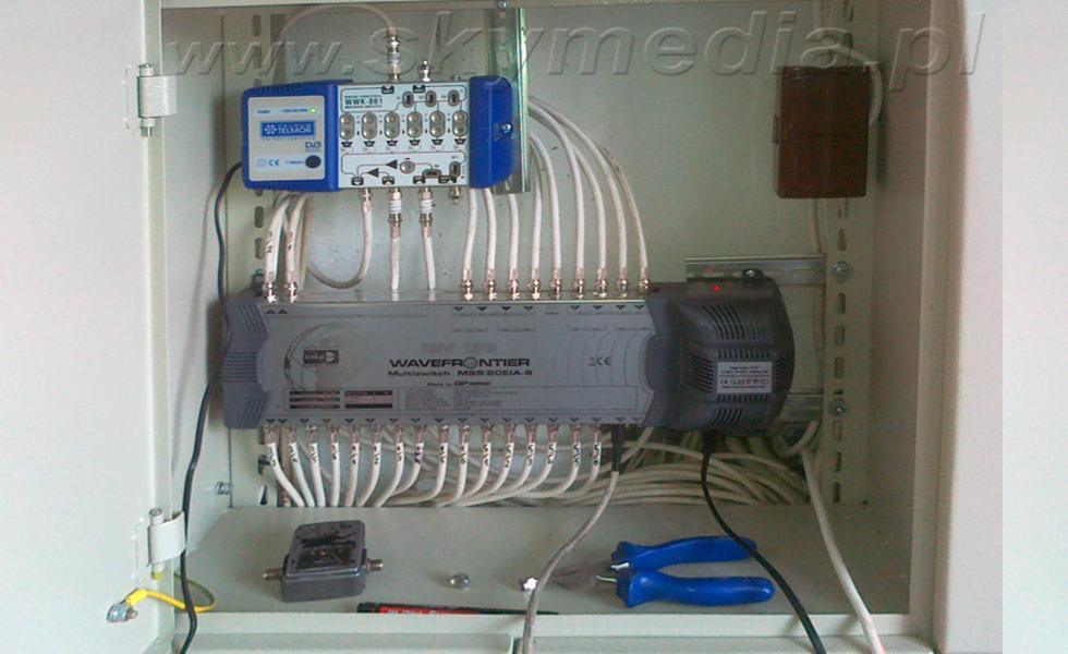 Instalacja multiswitcha Wavefrontier MSS 506IA-8 z podłączonymi kablami koncentrycznymi w szafce instalacyjnej w Katowicach. Widoczne narzędzia.