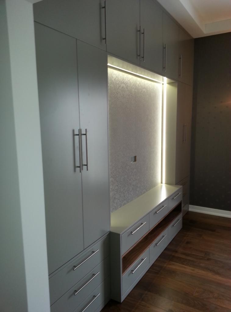 Szara szafa wnękowa z oświetleniem LED i szufladami, drewniana podłoga. Nowoczesny design, metalowe uchwyty.