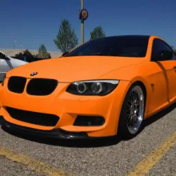 Pomarańczowe BMW E92 po zmianie koloru folią Plastidip, z czarnym dachem i karbonowym splitterem, zaparkowane na parkingu.