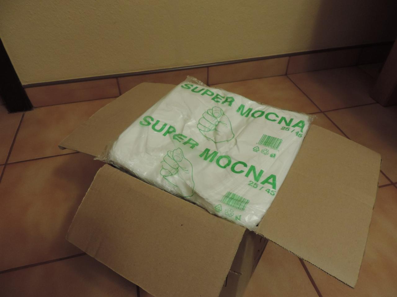 Kartonowe pudełko z zapakowanymi reklamówkami zrywkami 'Super Mocna' 25x45 w Myszkowie, widoczne na brązowej podłodze z płytek.
