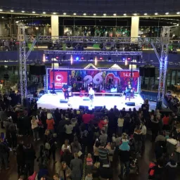 Zespół muzyczny na scenie podczas koncertu w centrum handlowym, oświetlenie sceniczne, tłum widzów