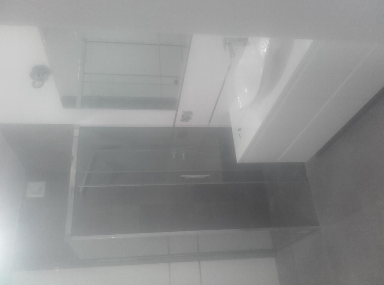 Nowoczesna kabina prysznicowa z szarymi płytkami, biała umywalka i szafka w łazience o minimalistycznym designie, widok z góry.