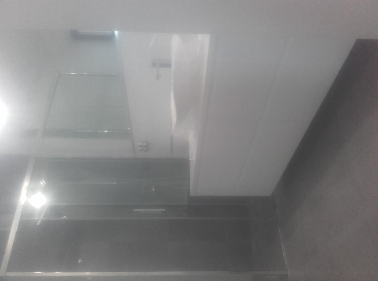 Nowoczesna łazienka z czarnymi płytkami i białą armaturą widziana pod kątem, z widoczną szklaną kabiną prysznicową i oświetleniem.