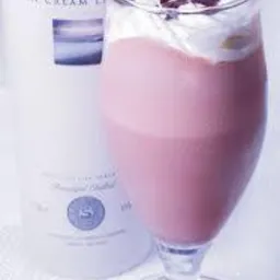 Kieliszek z różowym likierem Coole Swan, udekorowany bitą śmietaną i kawałkami czekolady, obok butelka tego samego likieru.