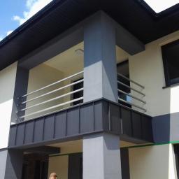 Balusmet Slawomir Janiak - Nowoczesny balkon z prostą, poziomą balustradą ze stali nierdzewnej, zamontowaną na ciemnoszarym panelu, widok z dołu na tle jasnej elewacji budynku.