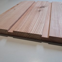 Usługi Stolarskie Patryk Torczyński - Fragment obrobionej deski z widocznymi słojami drewna i połączeniem na pióro i wpust, ukazujący precyzję wykonania.